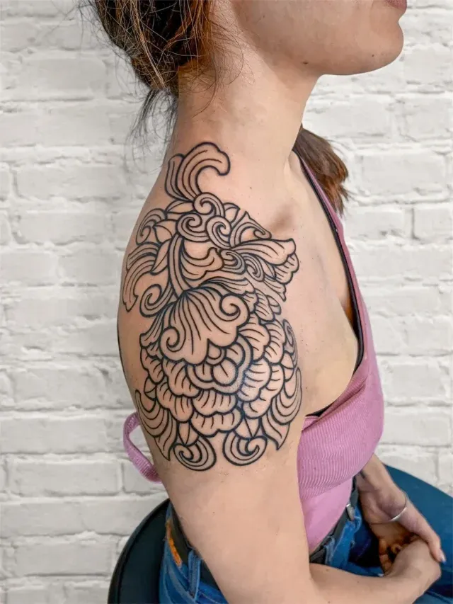 Ornamentales Tattoo: verschlungene Filigran-Ornamente über Schulter und Oberarm