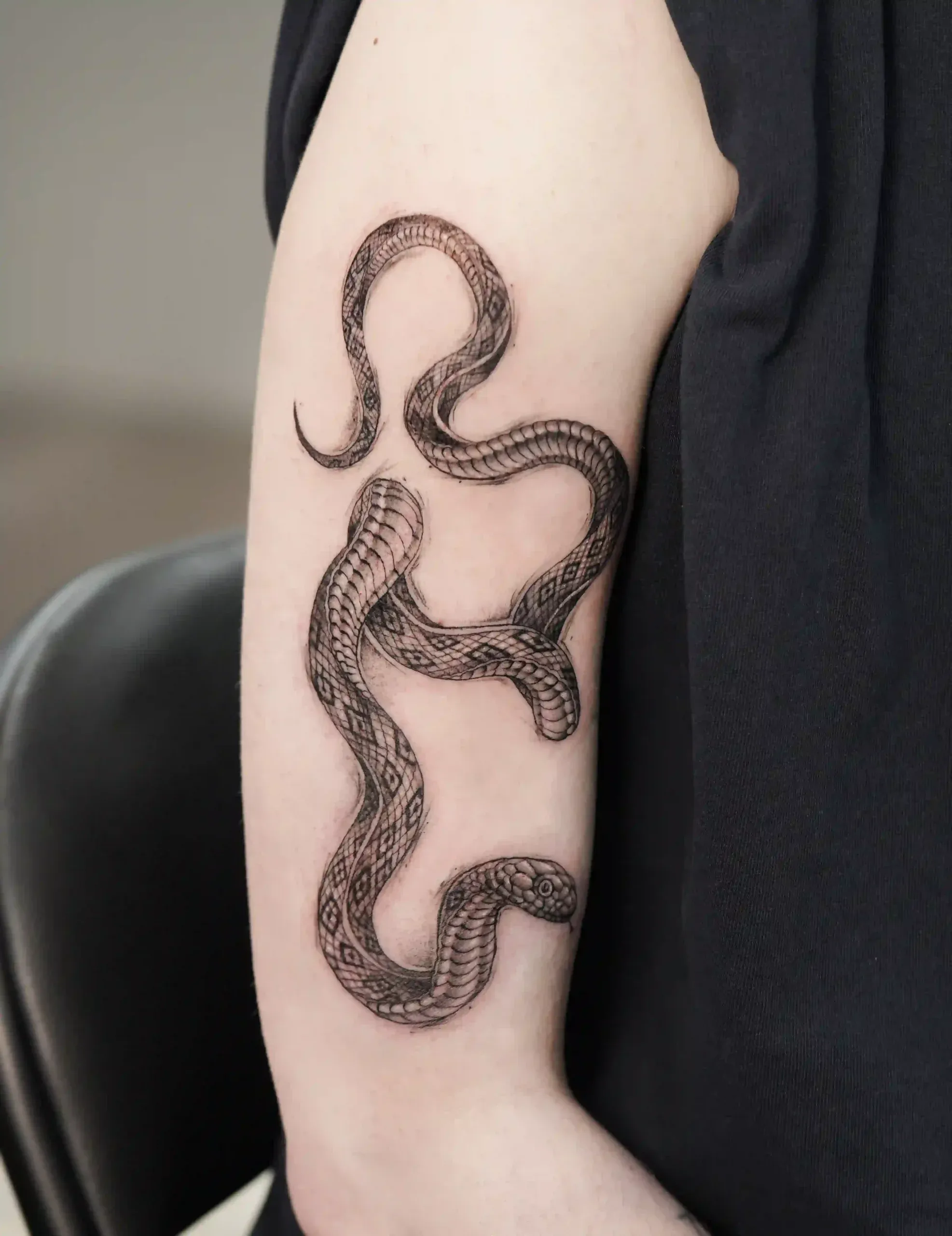 Mikrorealismus Tattoo: detailreiche Schlange in Schwarz-Grau auf dem Oberarm