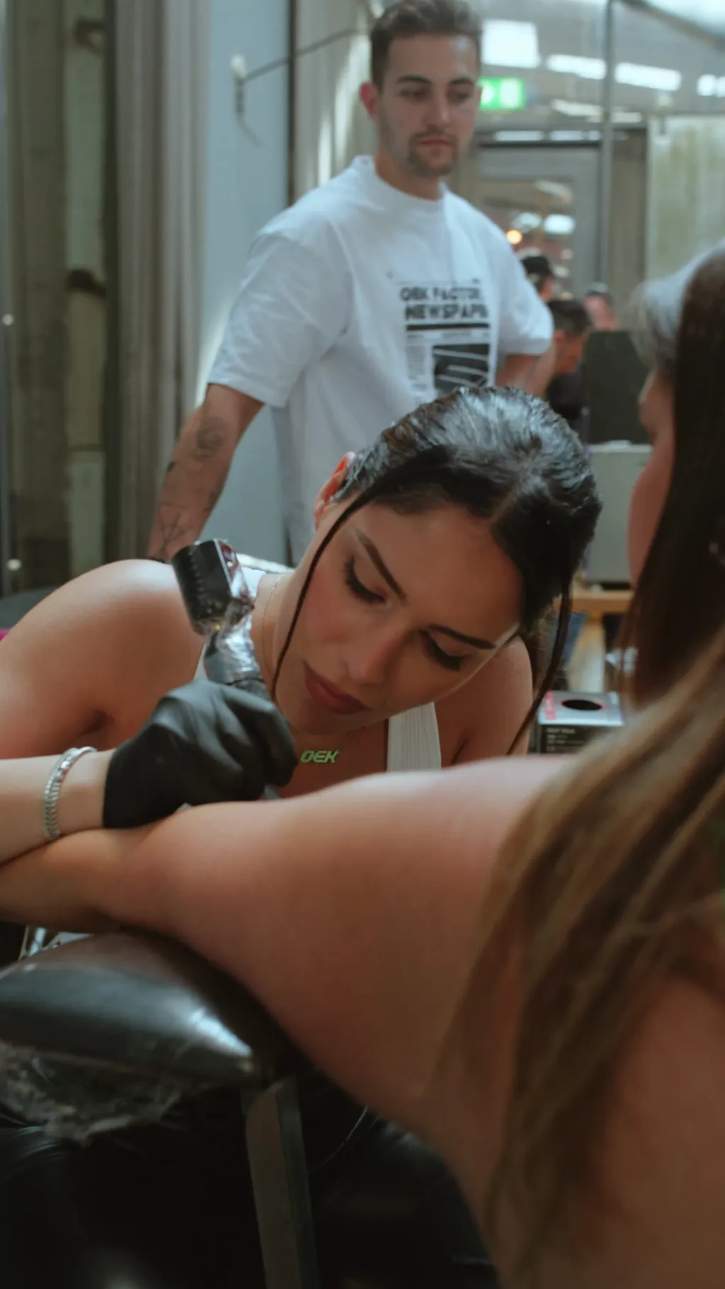 Eine Artistin von OEK Factory sticht einem Gast auf einem Markenevent ein Flash-Tattoo auf den Arm